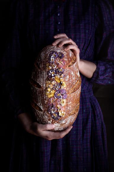 Ich habe seitliches, natürliches Licht verwendet und es in meinem Esszimmer fotografiert. Die Komplementärfarben Gelb und Violett harmonieren in diesem Bild gut mit der Textur des Brotes und dem Kleid.“